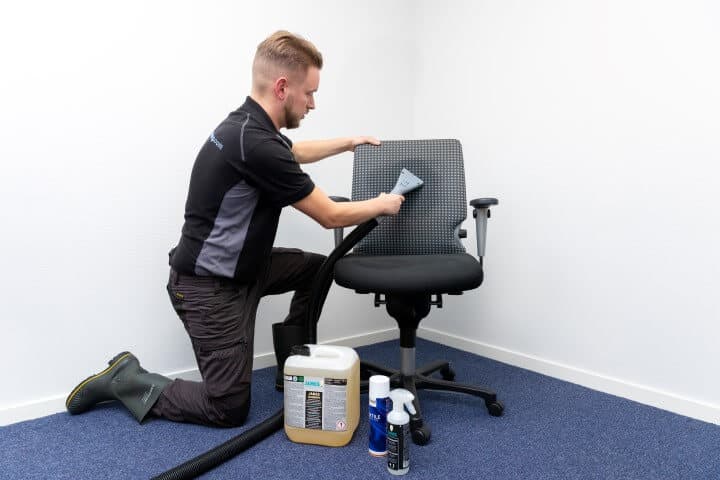 Specialist reinigt bureaustoelen met professionele sproei-extractie apparatuur